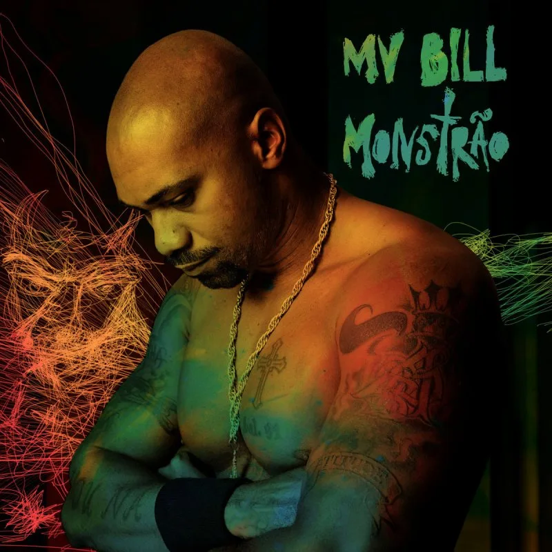 A capa do álbum 'Monstrão' mostra MV Bill em um close-up que revela seus braços musculosos e tatuados. Ele usa um colar de corrente dourada com um crucifixo e uma pulseira preta no pulso esquerdo. Sua cabeça está ligeiramente inclinada para baixo, e a iluminação em tons de laranja e verde cria um efeito dramático em sua pele. Ao fundo, linhas abstratas e coloridas em tons de vermelho, laranja, verde e azul se destacam em um fundo escuro. O título 'MV BILL Monstrão' está escrito em letras estilizadas no canto superior direito.