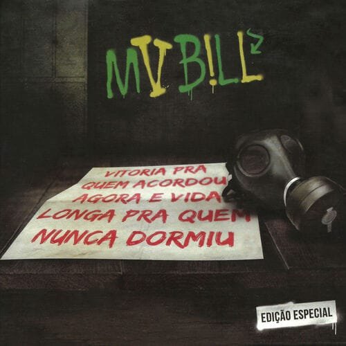 A capa do álbum 'Vitória pra Quem Acordou Agora e Vida Longa pra Quem Nunca Dormiu - Edição Especial' apresenta uma cena escura e urbana. Em destaque, sobre uma superfície, há um pedaço de papel com o título do álbum escrito em letras grandes e em tons de vermelho. Ao lado do papel, uma máscara de gás preta repousa. Ao fundo, uma parede escura exibe o nome 'MV BILL' pixado em verde e amarelo. No canto inferior direito da imagem, há um selo branco com a inscrição 'EDIÇÃO ESPECIAL'. A iluminação geral é baixa, criando uma atmosfera sombria.