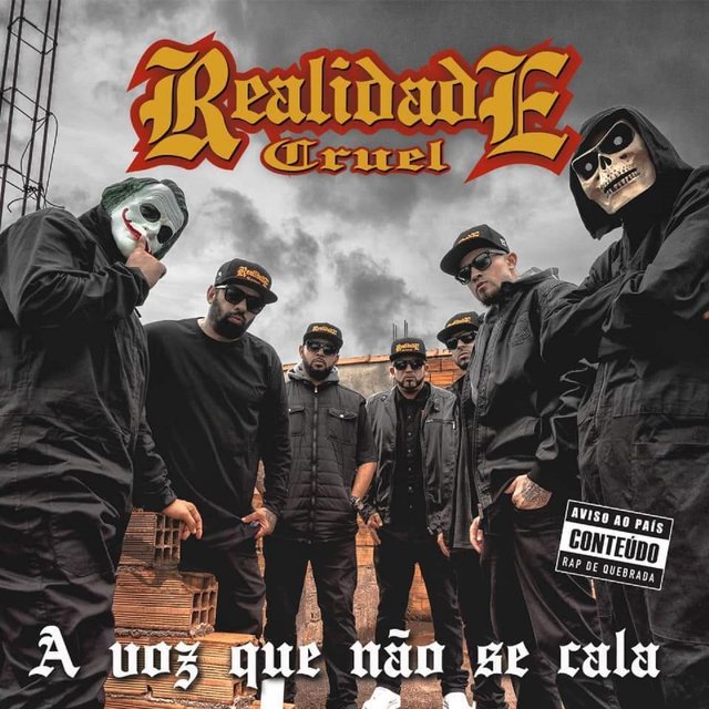 A capa de um álbum com sete pessoas em pé sobre um terreno de tijolos e ferragens. Cinco das pessoas vestem bonés pretos de aba reta e roupas escuras. Uma delas usa uma máscara de palhaço, e outra, uma máscara branca com um desenho de caveira. No centro da imagem, há um grande logo escrito 'Realidade Cruel' em letras góticas. No canto inferior direito, há um selo com 'AVISO AOS PAIS: CONTEÚDO RAP DE QUEBRADA'. Na parte de baixo da capa, há um letreiro branco com a frase 'A voz que não se cala'.