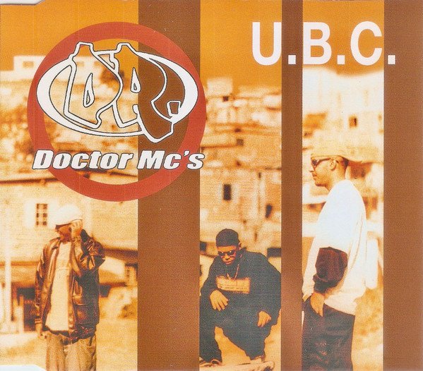 A imagem é a capa do single 'U.B.C.' do grupo 'Doctor Mc's', apresentando um design vibrante e urbano. O título do grupo aparece no canto superior esquerdo com um logotipo circular estilizado 'DR' sobre um fundo em tons de laranja e marrom. A sigla 'U.B.C.' está em destaque no canto superior direito. Na parte inferior, três integrantes do grupo estão retratados em um cenário de rua, com vestimentas típicas da cultura hip-hop, como bonés e óculos escuros, conferindo à capa uma estética característica do rap brasileiro, provavelmente do final dos anos 90 ou início dos anos 2000.